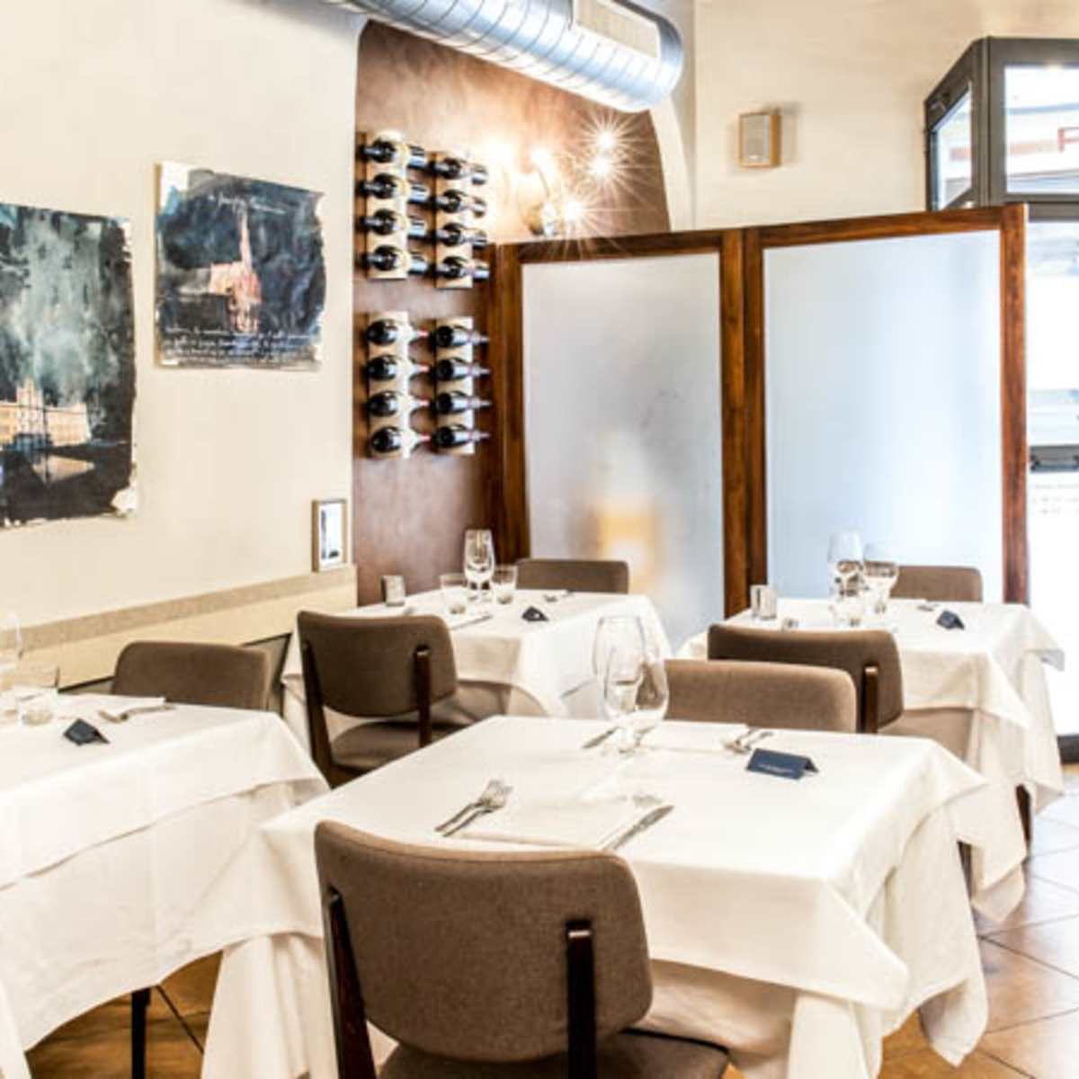 Sala interna di Antica Trattoria Cervetta, tavoli con tovaglie bianche e cantina a vista